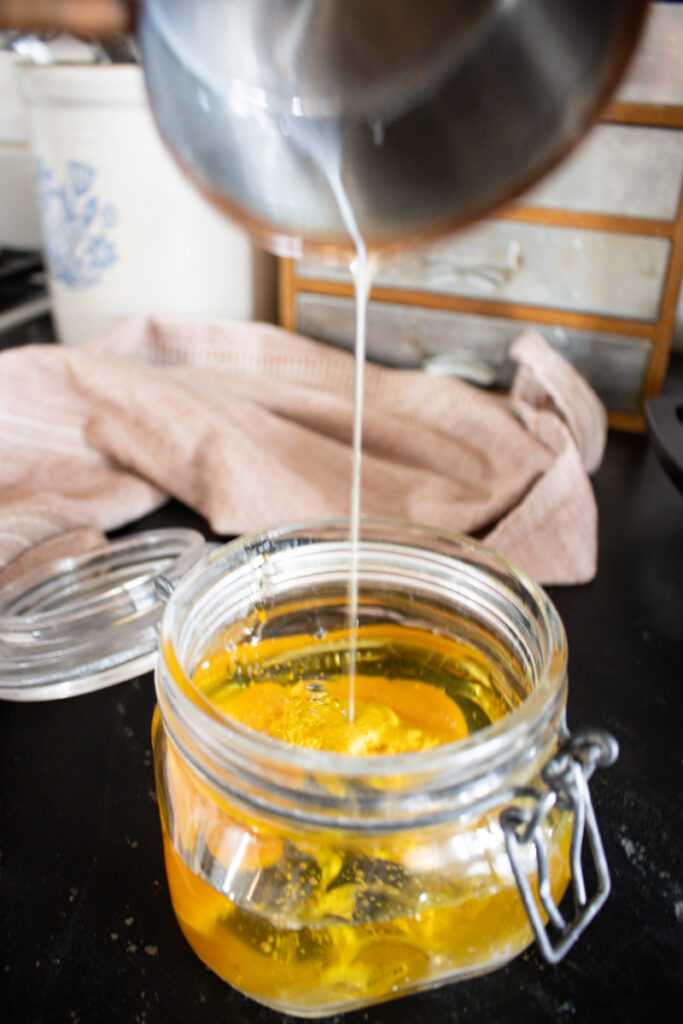 pouring avocado oil into a jar to make mayonnaise