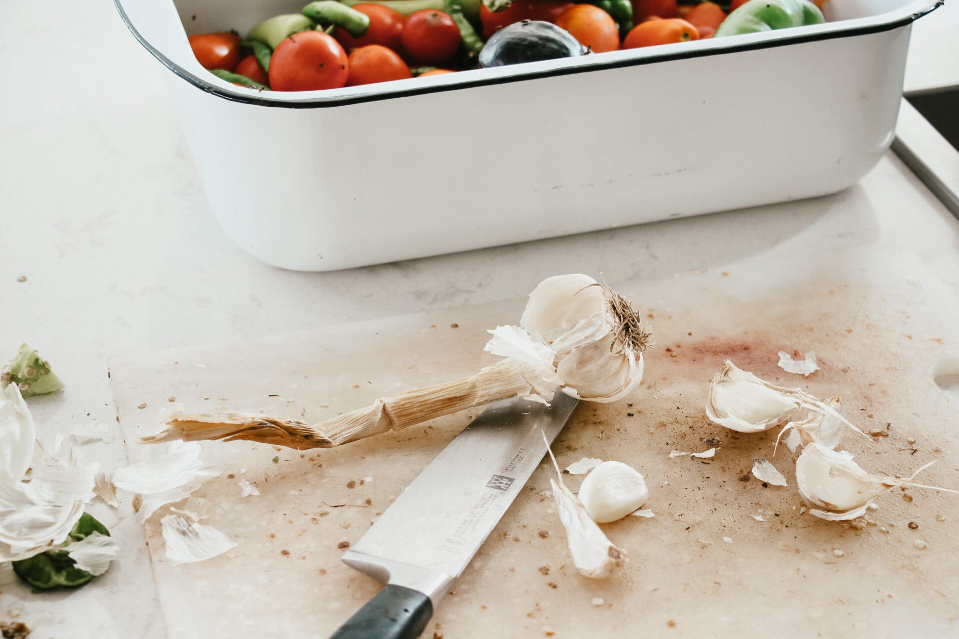 a white cutting board on a marble countertop chopping garlic cloves