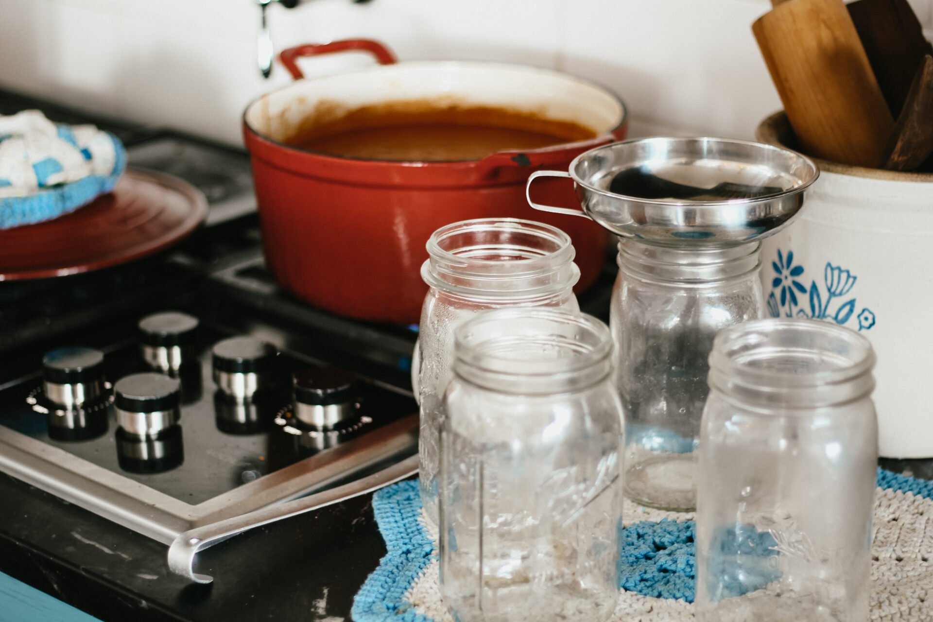 cleaning glass jars to use for canning sitting on a quilted doily on the black counter top next to the stove