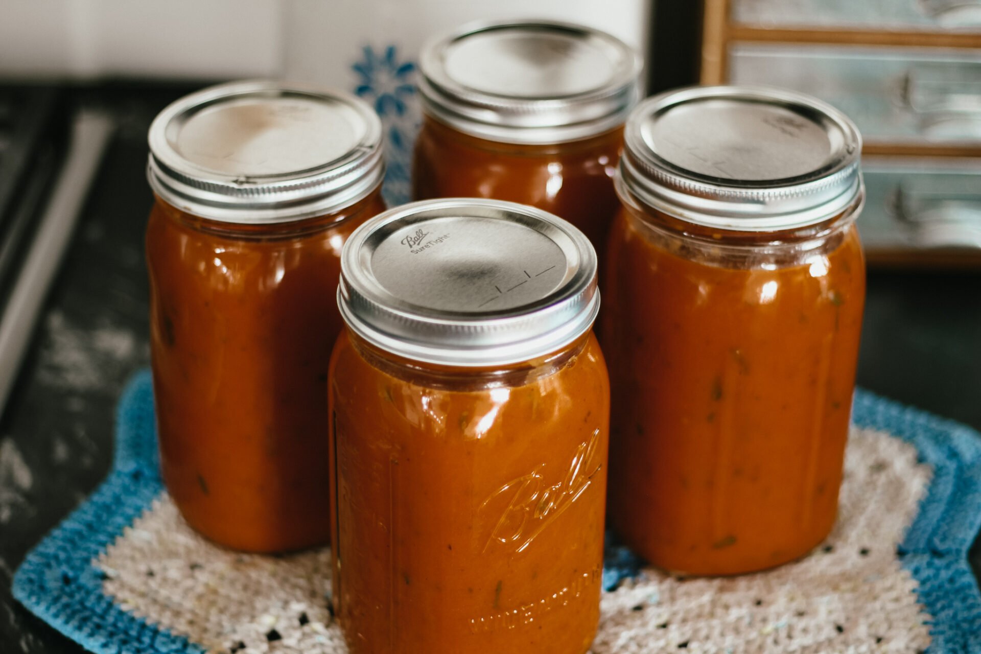 four jars of marinara sauce sitting on a black counter top with metal lids and rings around the jar