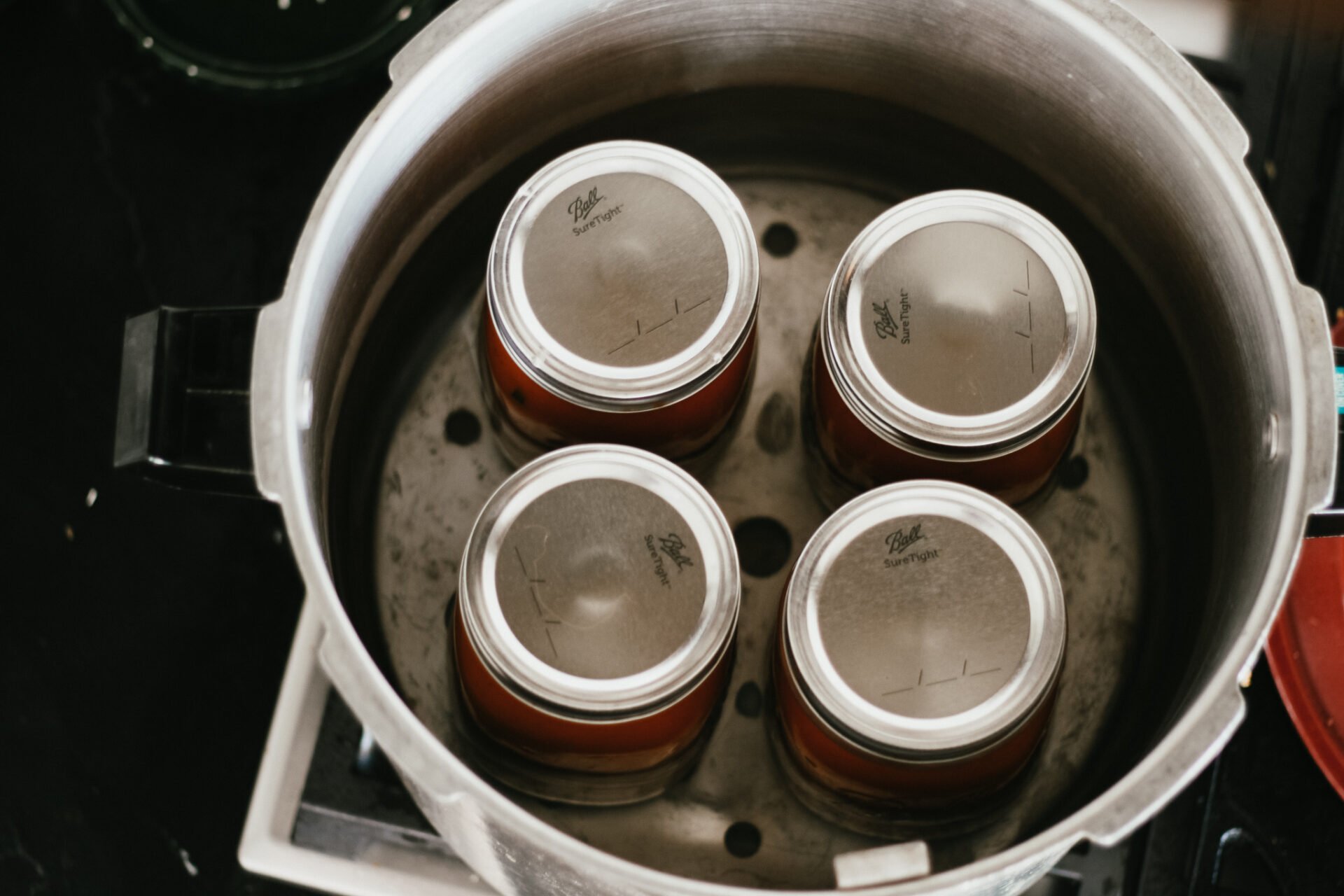 four jars of marinara sauce in a pressure canning with water in the canner