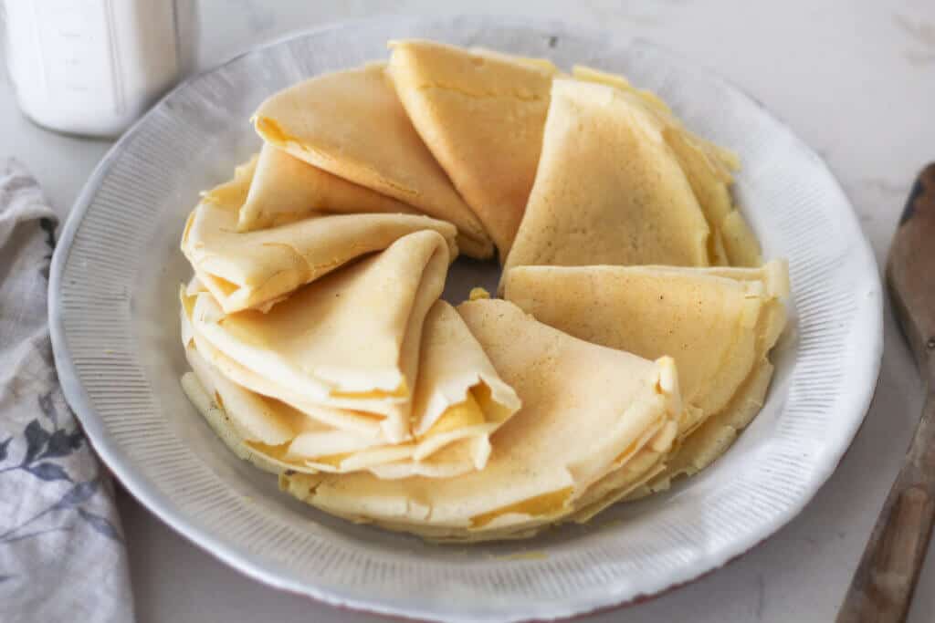 thin sourdough crepes folded and arranged in circle on plate.