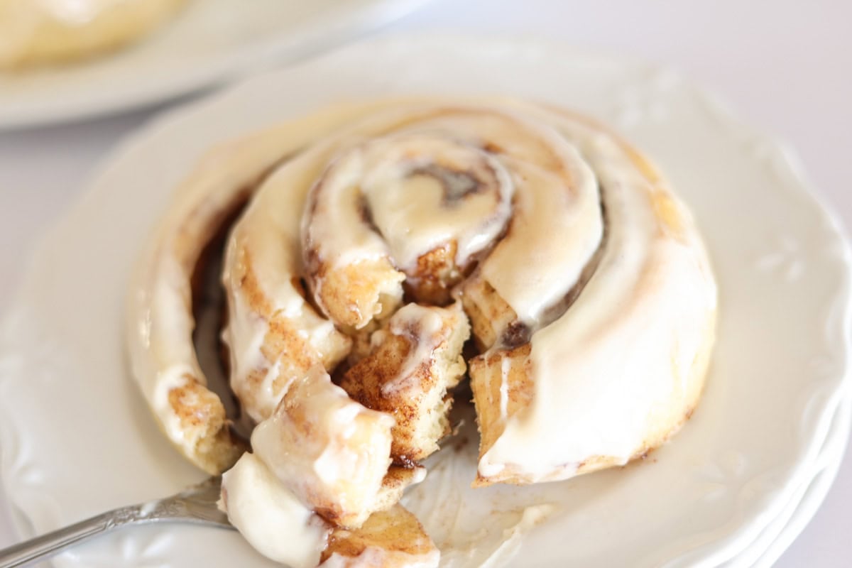 sourdough cinnamon roll with fork taking bite out.