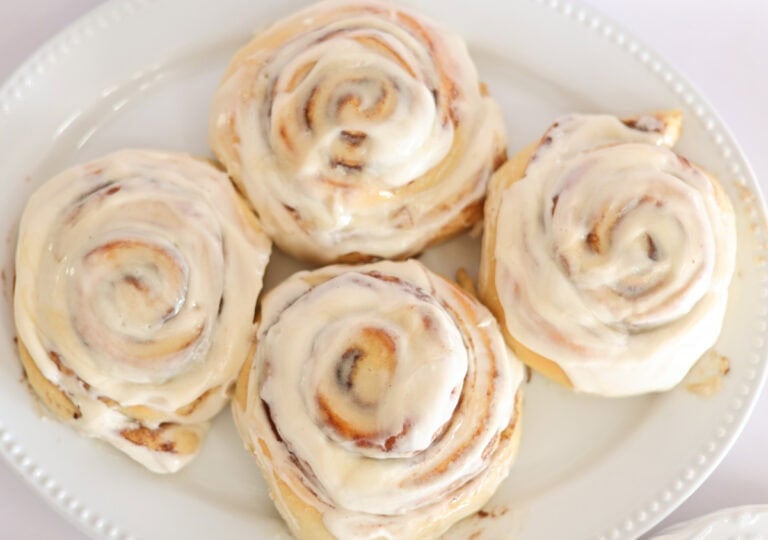 soft sourdough cinnamon rolls with cream cheese glaze on platter.