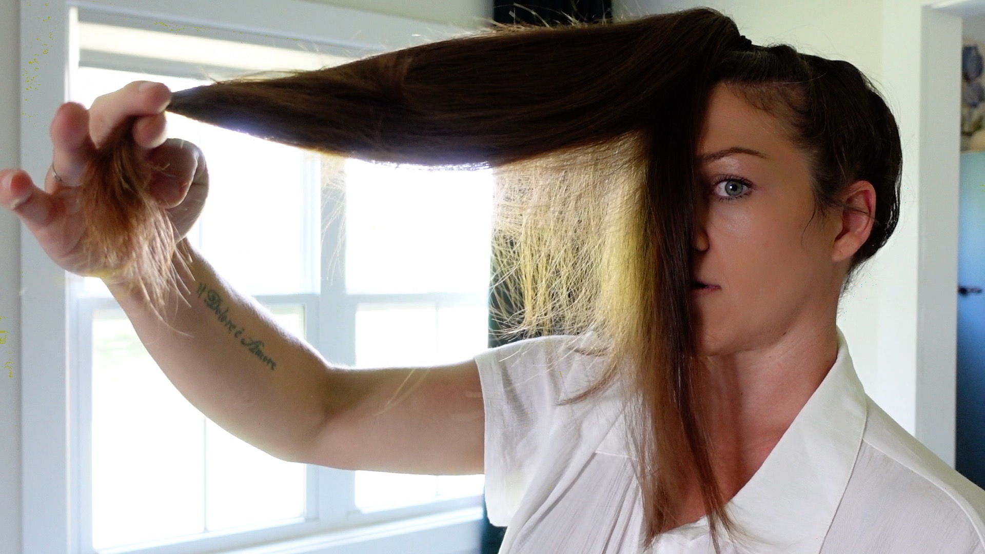a woman holding up her hair in a pony tail showing how to cut long layers 