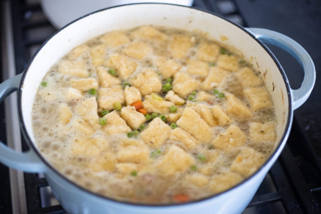 homemade dumplings boiling in a pot of chicken soup
