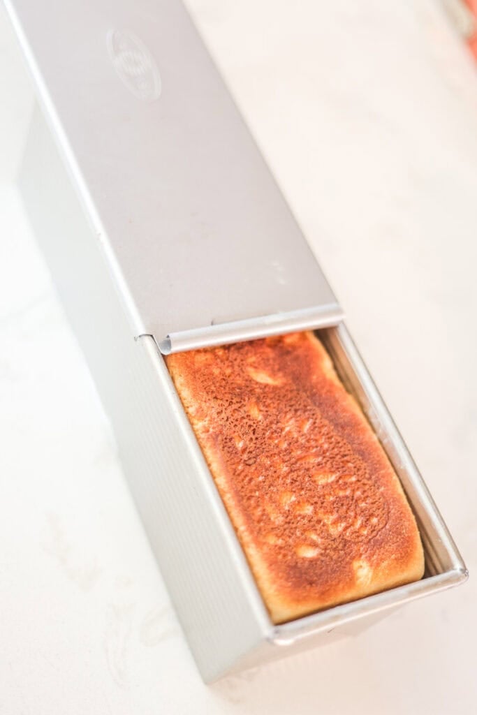 baked pullman loaf with lid pulled back halfway to cool.