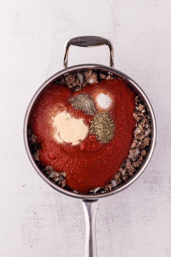 adding pasta sauce to the meat and other ingredients