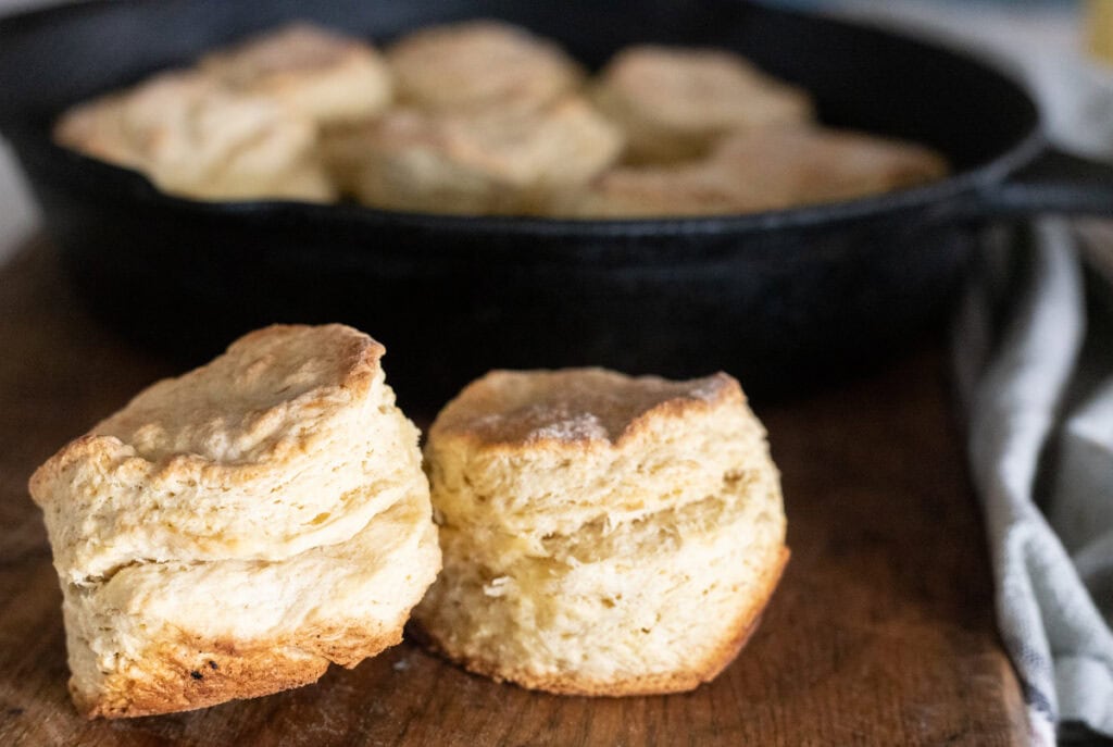 flaky sourdough discard biscuits in front of cast iron skillet.