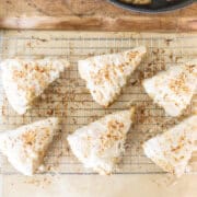 sourdough scones topped with vanilla glaze and coconut on a cooling rack.