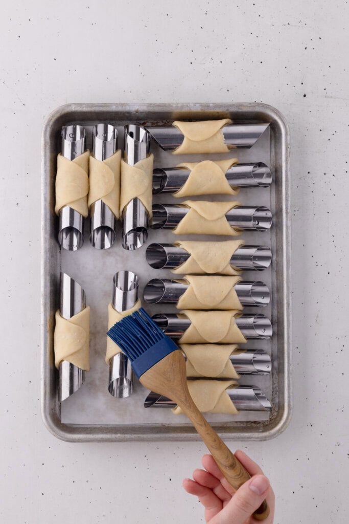 cannoli dough on forms brushed with egg wash to seal.