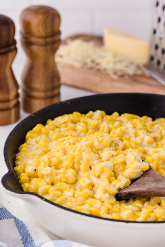 creamed corn in a skillet with a wooden spatula