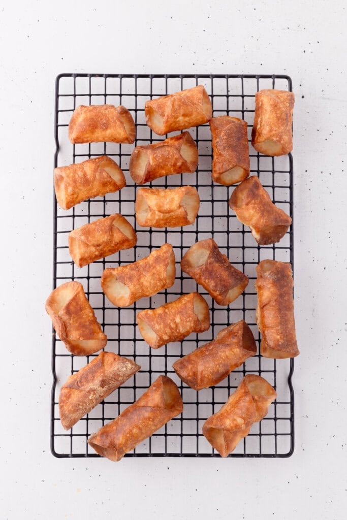 fried sourdough cannoli removed from molds cooling on wire rack.
