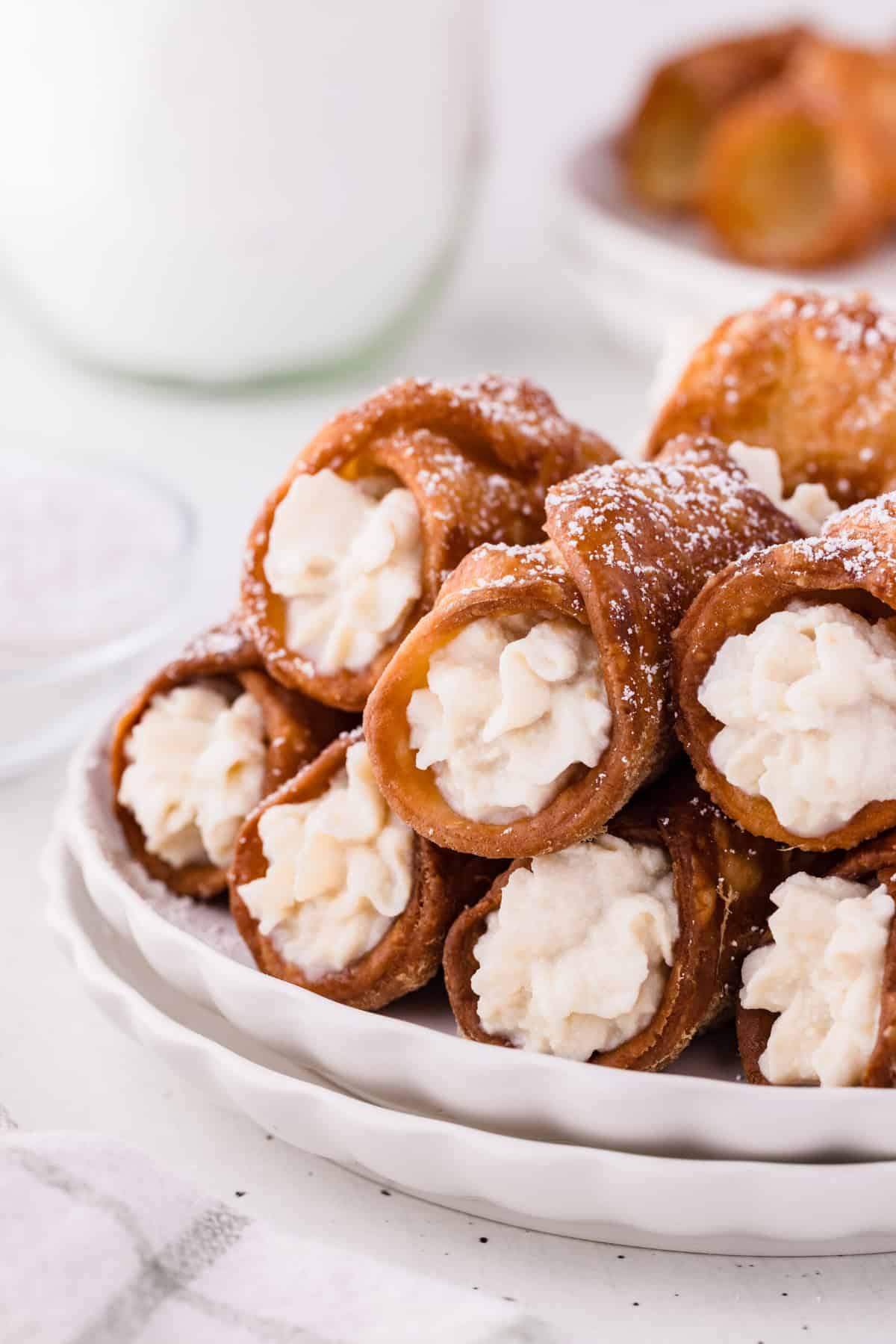 fried sourdough cannoli with ricotta cheese filling stacked on plate.