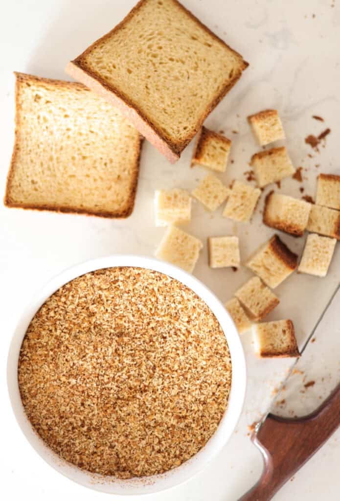 bowl of sourdough breadcrumbs with cubed bread and knife to side.