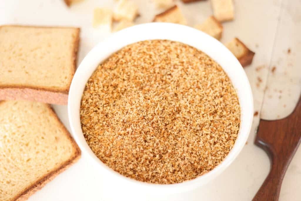 bowl of sourdough breadcrumbs with slices of bread to side.