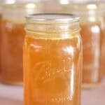 quart jar of pressure canned chicken bone broth with jars in background.