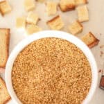 bowl of sourdough breadcrumbs with cubed bread in background.
