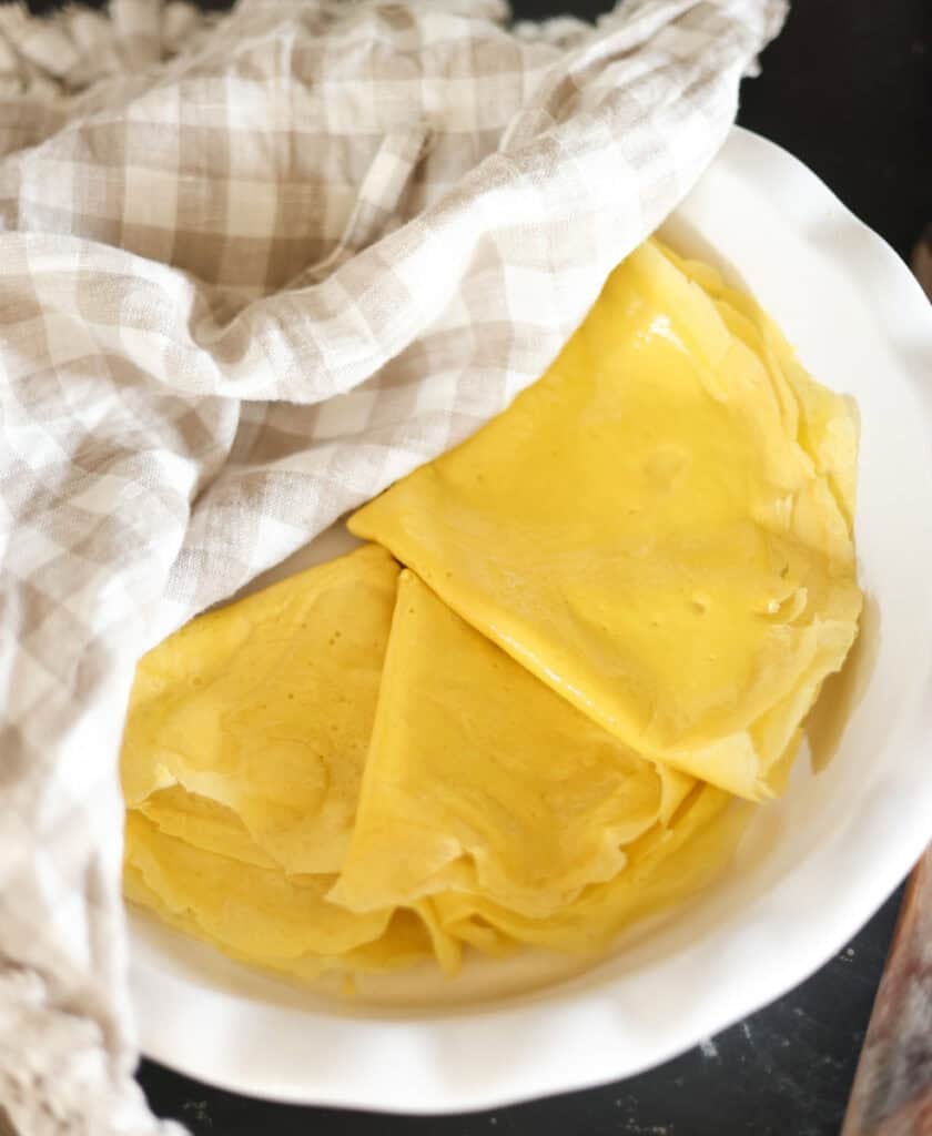 egg wraps folded and stacked in pie plate covered with tea towel.