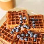plate of sourdougb protein waffles with blueberries and latte in background.
