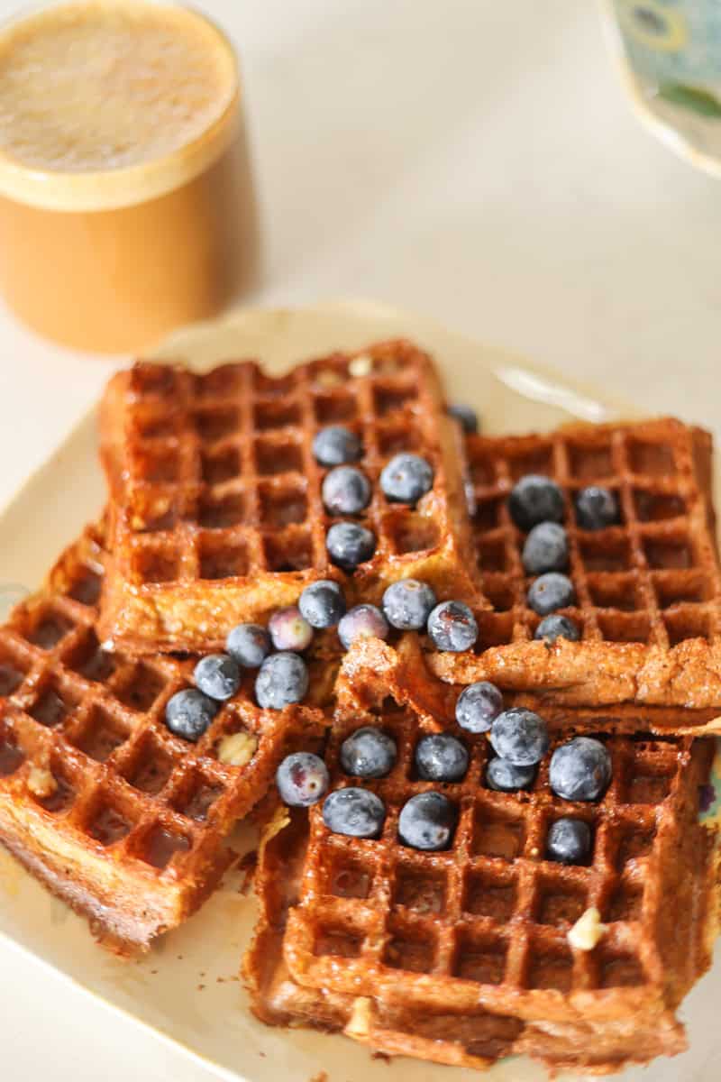plate of sourdougb protein waffles with blueberries and latte in background.