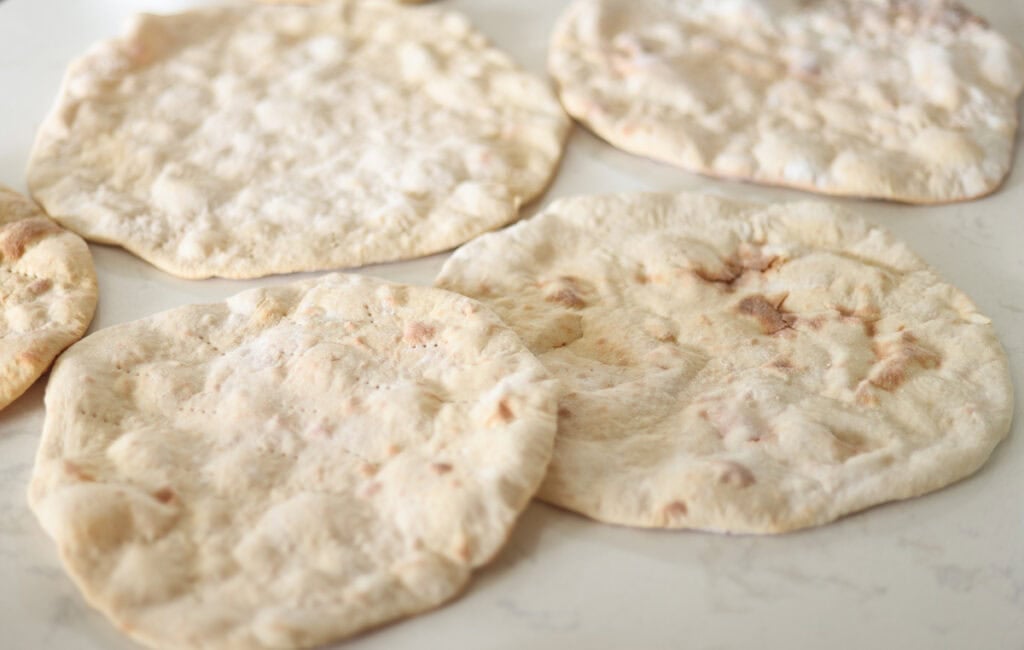 par baked high protein pizza crusts laid on counter.
