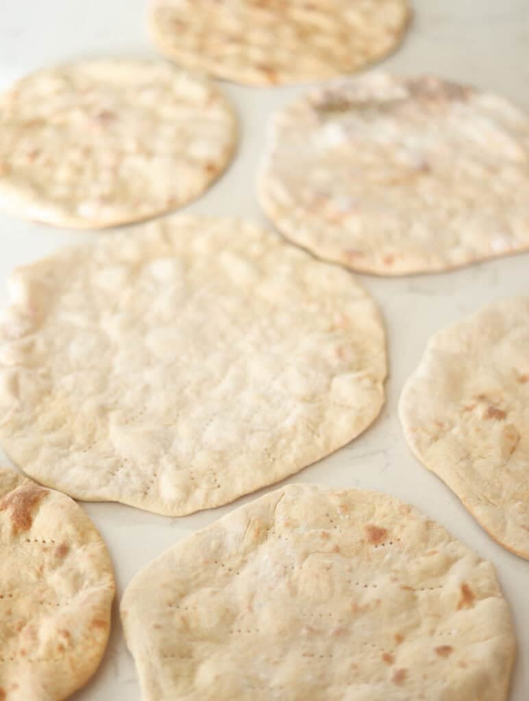 several par baked high protein pizza crusts cooling on counter.